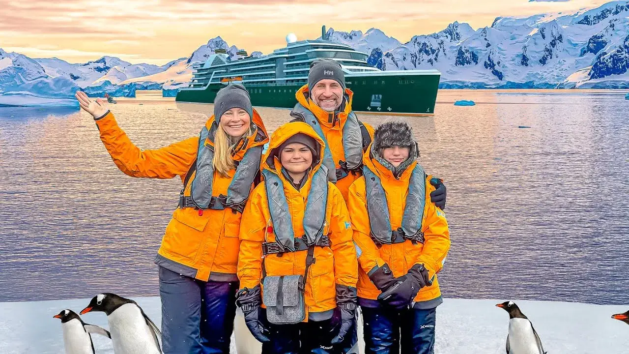 The Lockwood family standing on the shore of Antarctica with a cruise ship in the background
